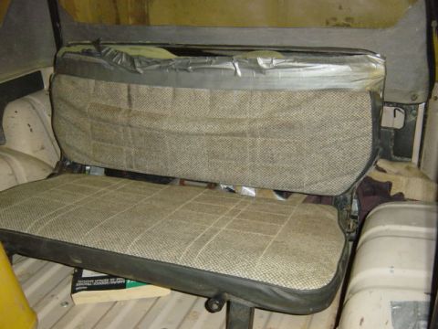 1987 Suzuki Samurai - The rear interior seats of a vehicle show plaid fabric upholstery with visible repairs using duct tape.