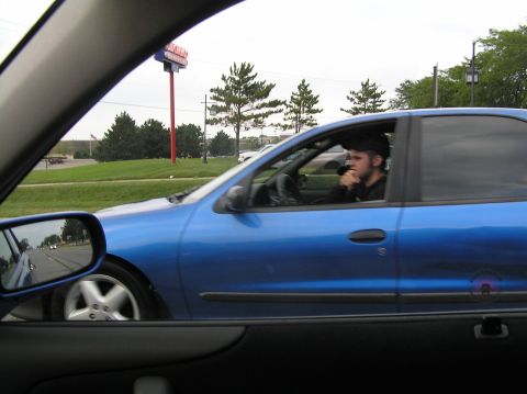 1996 Chevrolet Cavalier - Driver of a blue 1996 Chevrolet Cavalier sedan seen from another vehicle.