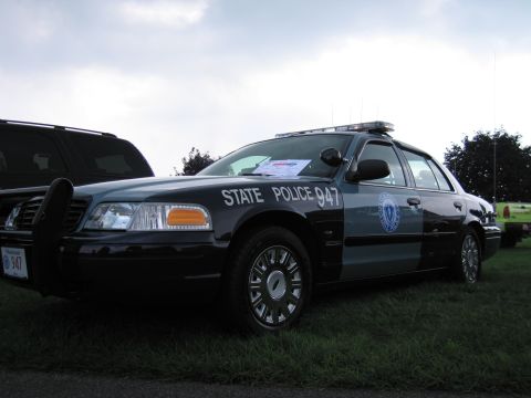1991 Ford LTD Crown Victoria - Close front-quarter view of a blue-gray State Police 947 Ford Crown Victoria cruiser with roof light bar.