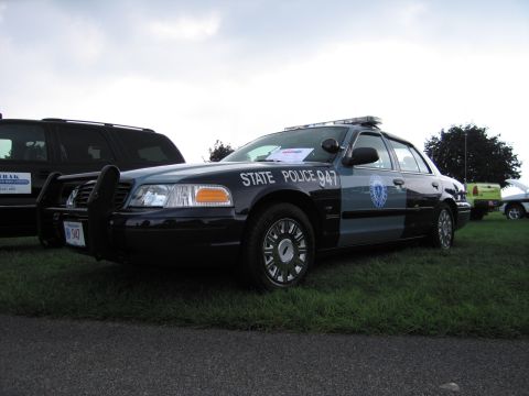 1991 Ford LTD Crown Victoria - blue-and-gray Ford Crown Victoria marked State Police 947 with push bar parked beside an SUV on grass.