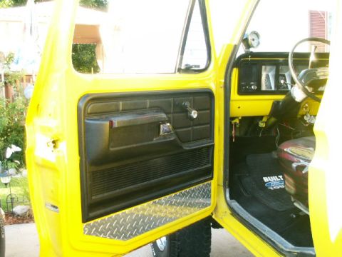 1979 Ford Bronco - Interior view of a yellow 1979 Ford Bronco, showing the door panel, dashboard, and driver's seat.