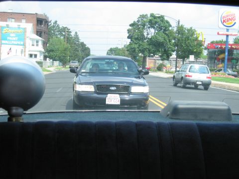 1991 Ford LTD Crown Victoria - dark Ford Crown Victoria with oval grille badge drives toward the camera on a street near a Burger King.