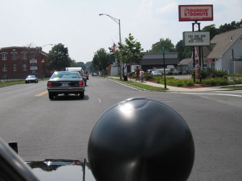 1991 Ford LTD Crown Victoria - dark sedan drives down a street near a Dunkin' Donuts sign, viewed past a black spherical object.