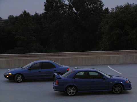 1996 Chevrolet Cavalier - Two blue sedans are parked side-by-side in an outdoor lot as daylight fades.