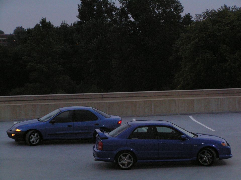 Two blue sedans parked in a lot at dusk
