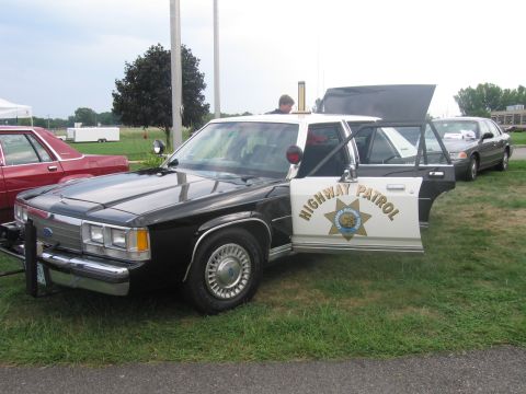 1991 Ford LTD Crown Victoria - black-and-white Ford police sedan marked Highway Patrol sits on grass with its hood and front door open.