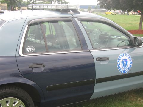 1991 Ford LTD Crown Victoria - Close-up of a blue-and-gray police cruiser's rear door bearing a Massachusetts State Police seal and a CVN window sticker.