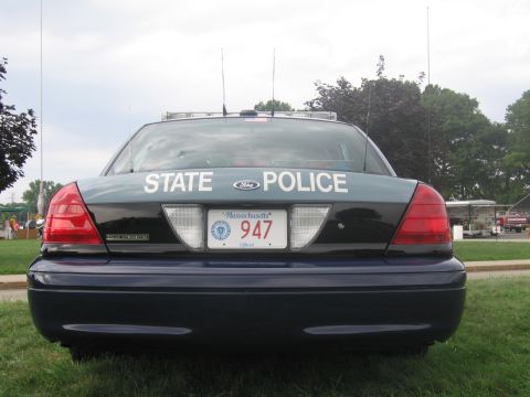 1991 Ford LTD Crown Victoria - Rear view of a black Ford sedan lettered STATE POLICE with a Massachusetts plate numbered 947 on grass.