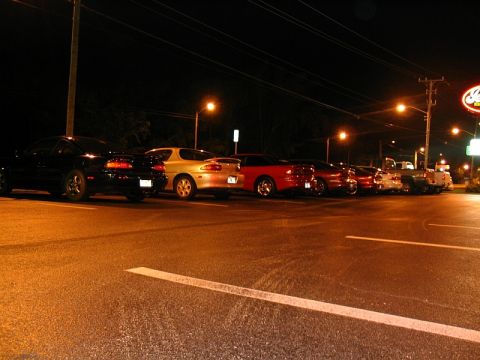1997 Ford Probe - A line of cars, including two Ford Probes, are parked in a lot under streetlights at night.