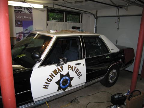 1991 Ford LTD Crown Victoria - black-and-white sedan lettered Highway Patrol with a California Highway Patrol star sits parked inside a home garage.