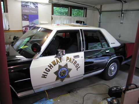 1991 Ford LTD Crown Victoria - black-and-white Highway Patrol sedan with a CHP door star and roof light bar sits angled inside a garage.