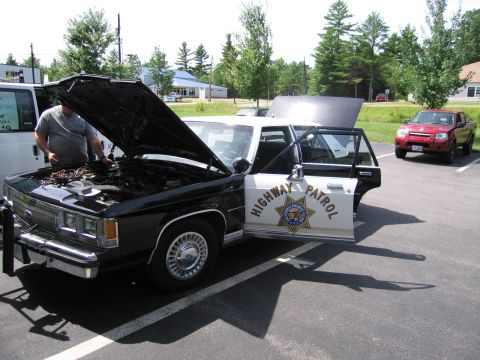 1991 Ford LTD Crown Victoria - black-and-white Ford Highway Patrol sedan with a CHP door star sits in a paved lot with its hood and rear door open beside a red SUV.