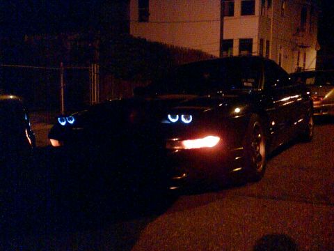 1997 Ford Probe - A black car is parked on a street at night, illuminated by its headlights.