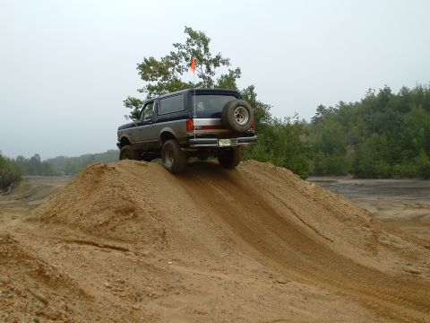 1995 Ford Bronco - Ford Bronco navigates an off-road course, ascending a sandy incline.