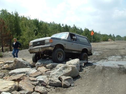 1995 Ford Bronco - A Ford Bronco navigates a rocky obstacle course on a dirt road.