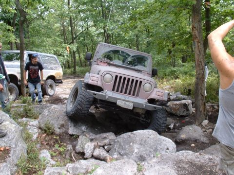 1995 Ford Bronco - Jeep Wrangler tackling a difficult off-road obstacle with another vehicle nearby.