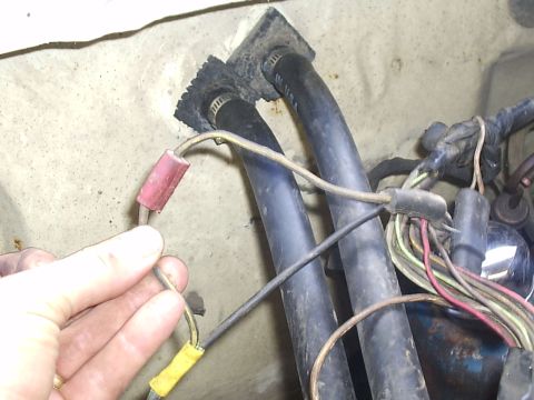 1979 Ford F-150 - Close-up view of a vehicle's wiring harness and rubber hoses, with a hand holding a wire connector.