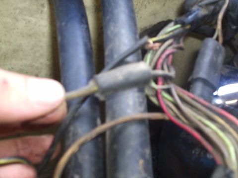 1979 Ford F-150 - Close-up of a hand holding a disconnected wire from a complex automotive wiring harness.