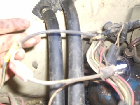 1979 Ford F-150 - A close-up view of the engine bay shows a tangle of wires and hoses, with a hand holding a loose wire.