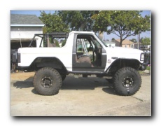1987 Ford Bronco - Side view of a white 1987 Ford Bronco modified for off-road use with lifted suspension.