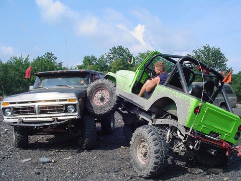 1979 Ford Bronco - Two off-road vehicles are engaged in an off-roading activity, with one vehicle positioned on top of the other.