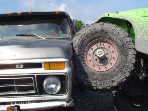 1979 Ford Bronco - Front view of a gray Ford truck with a large off-road tire from a green vehicle to its right.