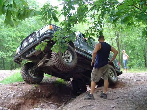 1979 Ford Bronco - Off-road SUV with lifted suspension is tilted precariously while navigating a ditch.
