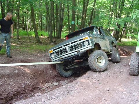 1979 Ford Bronco - Ford Bronco attempts to navigate a challenging off-road obstacle, requiring assistance from a tow strap.