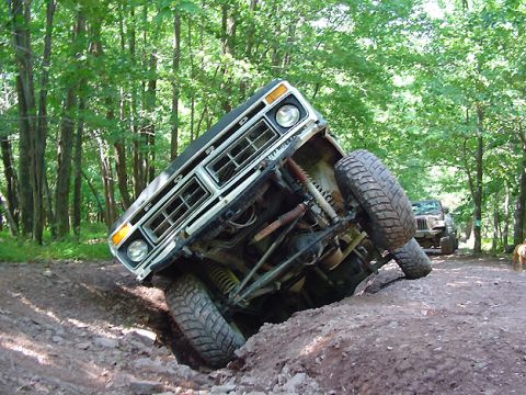 1979 Ford Bronco - This 1979 Ford Bronco is navigating a challenging off-road course, tilted precariously on a muddy incline.