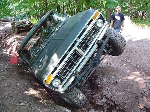 1979 Ford Bronco - A dark green 1978 Ford Bronco is stuck in a ditch while off-roading, with another vehicle visible in the background.