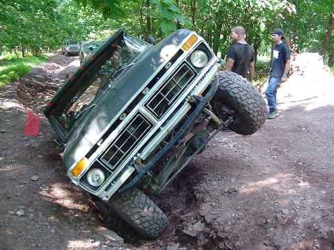 1979 Ford Bronco - This 1979 Ford F-Series truck is tilted precariously in a ditch, with another vehicle visible in the background.