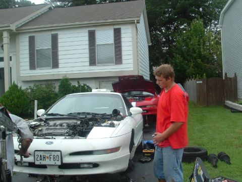 1996 Ford Probe - A 1996 Ford Probe is being worked on, with its engine exposed. A second car is visible in the background.