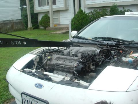 1996 Ford Probe - The engine bay of a white car is visible, with an engine hoist positioned overhead.