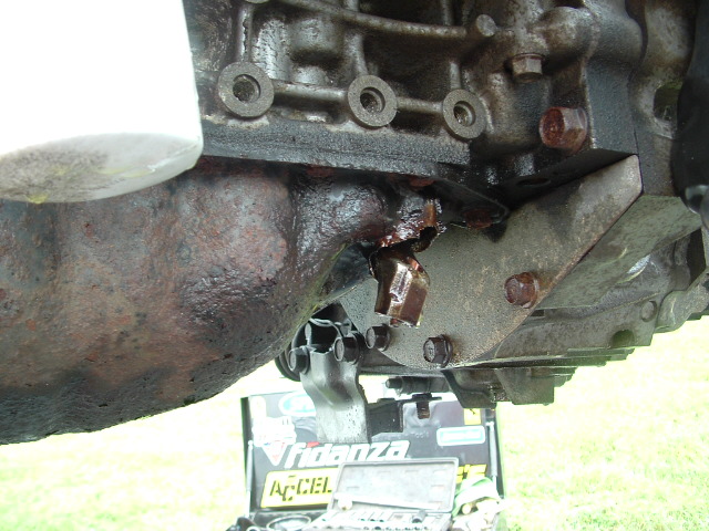 Engine oil filter attached to engine block with visible damage to a bracket