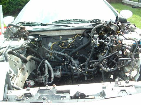 1996 Ford Probe - The engine bay of a vehicle with the hood open, revealing a complex network of wires and engine parts.