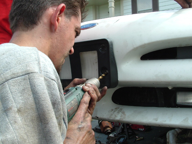 White 1996 Ford Probe bumper being drilled by a man