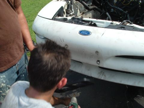 1996 Ford Probe - A person works on the front bumper of a white 1996 Ford Probe.