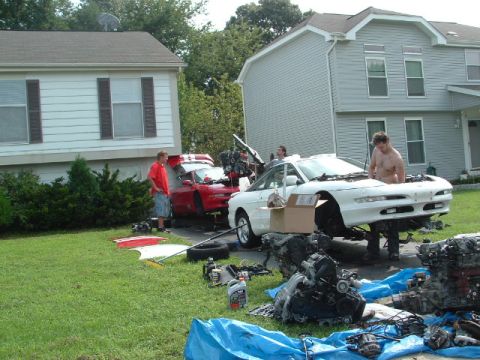 1996 Ford Probe - Two Ford Probes are undergoing engine work in a residential driveway, with parts scattered on the lawn.