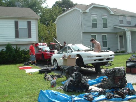 1996 Ford Probe - Two cars, a white 1996 Ford Probe and a red sports car, are undergoing engine work in a suburban driveway.