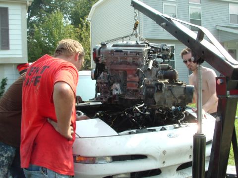 1996 Ford Probe - Mechanics work on removing an engine from a 1996 Ford Probe using an engine hoist.