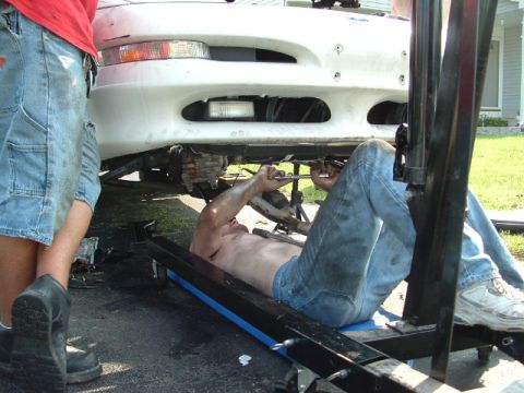 1996 Ford Probe - A man works on the underside of a 1996 Ford Probe, likely during an engine swap.
