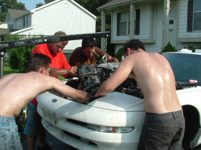 Guys pulling engine out of a 1996 Ford Probe with an engine hoist
