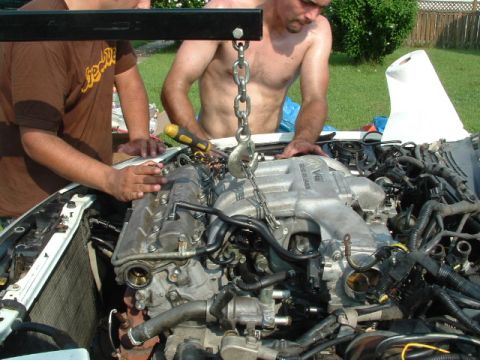1996 Ford Probe - Engine removal in progress with an engine hoist and two people working.
