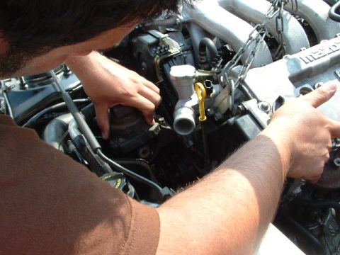 1996 Ford Probe - Mechanic's hands are seen working on a car engine, with a chain attached to the engine block.