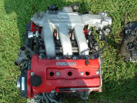1996 Ford Probe - A Mazda V6 engine, identified by the 'Mazda' logo on the red valve cover, is displayed outdoors.