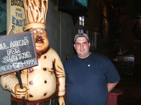 1998 Ford Taurus - A man poses next to a large chef statue holding a sign that reads 'ALL AHEAD FOR SEATING' and a phone number.