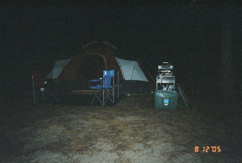 1990 Ford Bronco - flash-lit night scene of a campsite shows a dome tent, folding camp chairs, and a cooler with gear, dated August 12, 2005.