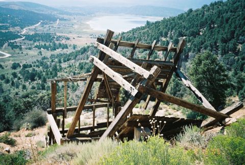 1990 Ford Bronco - collapsing weathered wooden frame structure stands on a brushy hillside above a distant lake and valley.
