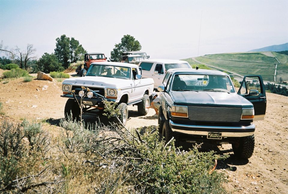 Lifted pickup with billet grille and lifted SUV parked on a dirt ridge