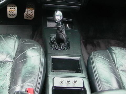 1992 Ford Taurus - The interior of a car shows leather seats, a gear shifter, and aftermarket pedals.